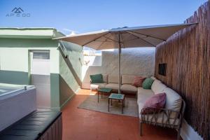a patio with a couch and an umbrella at Casa de los hermanos in Almuñécar