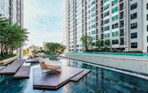 een zwembad van het hotel met stoelen en gebouwen bij 2 Bed Room, Large Living Room @ Central Pattaya in Pattaya