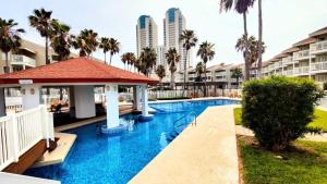 una piscina en un complejo con palmeras y edificios en GULFPOINT 1303 condo en South Padre Island