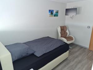 1 dormitorio con 1 cama y 1 silla en Gästehaus in der Daimlerstadt, en Schorndorf