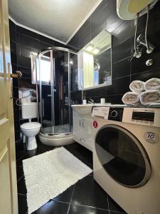 łazienka z prysznicem i pralką w obiekcie Apartmani Andric w mieście Trebinje
