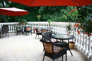 a patio with tables and chairs and an umbrella at Rezydencja Grawert Boutique & Spa in Lądek-Zdrój