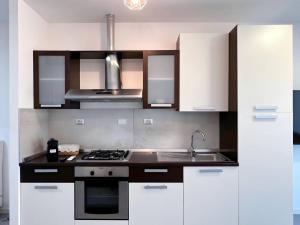 una cucina con mobili bianchi e un forno a piano cottura di Non ti scordar di me #1 a Pieris
