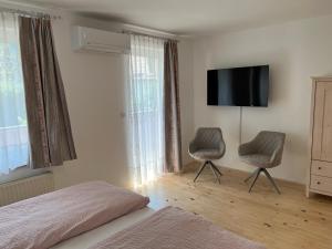 a bedroom with two chairs and a flat screen tv at Rooms Hrominc in Bled