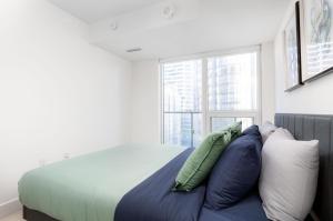 um quarto com uma cama com almofadas e uma janela em 2 Beds - Sleeps 3 beside U of T! em Toronto