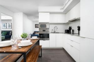 una cucina con armadi bianchi e tavolo in legno di 2 Beds - Sleeps 3 beside U of T! a Toronto
