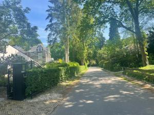 une route dans un parc avec une maison et des arbres dans l'établissement Huisje Hendrik, à Baarn