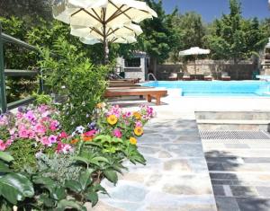 un jardín con un banco y flores junto a una piscina en Elia Village by Irida Iris Group, en Plomari