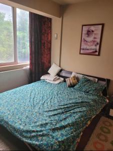 ein Schlafzimmer mit einem Bett mit einer blauen Decke und einem Fenster in der Unterkunft Apartament Untold Festival in Cluj-Napoca