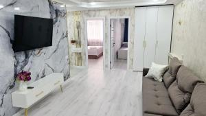 uma sala de estar com um sofá e uma televisão na parede em 3х-ком Люкс в центре Шымкента Проспект Б Момышулы 4 em Shymkent