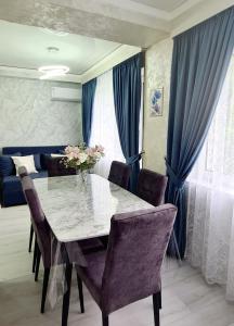 uma sala de jantar com mesa e cadeiras e cortinas azuis em 3х-ком Люкс в центре Шымкента Проспект Б Момышулы 4 em Shymkent