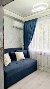 um sofá azul num quarto com uma janela em 3х-ком Люкс в центре Шымкента Проспект Б Момышулы 4 em Shymkent