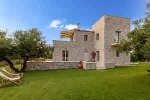 a large stone house with a lawn in front of it at EFMAR EXCLUSIVE RESIDENCES in Gythio