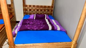 1 cama con edredón morado y azul en Roots cottages and campsite, 