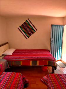 Arco Wasi Hospedaje Amantani في بونو: غرفة نوم مع سرير وملاءات حمراء ونافذة