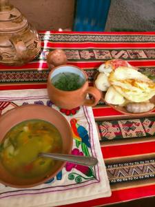Arco Wasi Hospedaje Amantani في بونو: طاولة مع وعاء من الحساء وصحن من الطعام