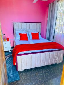 een roze slaapkamer met een groot bed met rode kussens bij The central Heartbeat Haven Intercity in Dar es Salaam