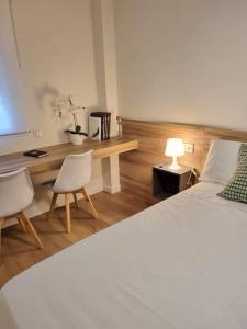 a bedroom with a bed and a desk with two chairs at Balcón del Malecón in Murcia