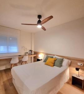 a bedroom with a white bed with a ceiling fan at Balcón del Malecón in Murcia