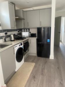a kitchen with a black refrigerator and white cabinets at Your perfect place of comfort in Goodmayes