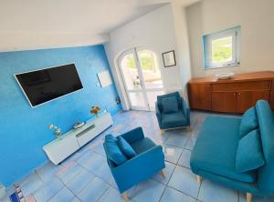 a living room with two blue chairs and a flat screen tv at Villa Nereide - Baia Santa Reparata in Santa Reparata