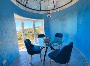 a dining room with a glass table and blue chairs at Villa Nereide - Baia Santa Reparata in Santa Reparata
