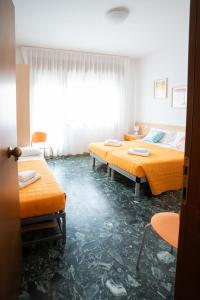 two beds in a room with orange sheets at Residence Rex in Chioggia