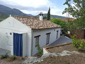 a small white house with a blue door at Casita de Campo El Bujeo in Quéntar