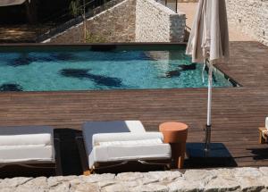 einen Pool mit 2 Liegestühlen und einem Sonnenschirm in der Unterkunft Boutique Hôtel Responsable et Restaurant Basgi Basgi, ouverture mai 2024 in Saint-Florent