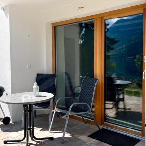 a patio with two chairs and a table and glass doors at Chalets Zöhrer - Wohnen am Wasser in Weissensee