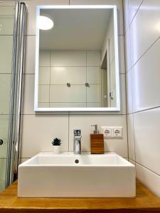 uma casa de banho com um lavatório branco e um espelho. em Chalets Zöhrer - Wohnen am Wasser em Weissensee