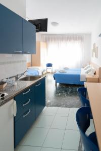 a kitchen with blue cabinets and a room with a bed at Residence Rex in Chioggia