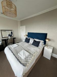 a bedroom with a large white bed with a blue headboard at Tides Reach Guest House in The Mumbles