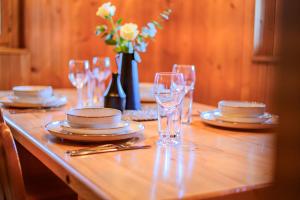 a table with plates and glasses and a vase of flowers at Relax house AVUS with Sauna in Slap ob Idrijci
