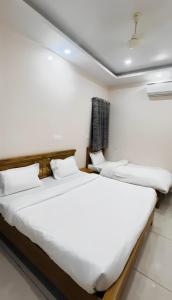two beds in a room with white walls at Pavan Guest Inn in Vrindāvan