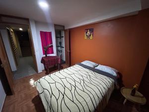 a bedroom with a bed in a room with orange walls at El Hospedaje del Muki in Ollantaytambo