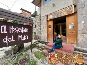 a woman sitting on the steps outside of a building at El Hospedaje del Muki in Ollantaytambo