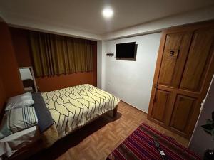 ein kleines Schlafzimmer mit einem Bett und einem Fernseher in der Unterkunft El Hospedaje del Muki in Ollantaytambo + 1 Foto