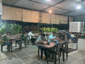 a group of people sitting at tables in a restaurant at Paarijat PG in Udaipur