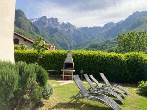 eine Reihe von Stühlen in einem Garten mit Bergen im Hintergrund in der Unterkunft Villa Sasso Cavallo in Mandello del Lario