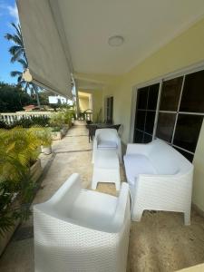 a patio with two white couches and a table at Las Palmeras by Graziano in Boca Chica