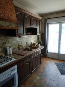 a kitchen with wooden cabinets and a sink and a window at Jolie longère au calme proche du Futuroscope in Saint-Georges-lès-Baillargeaux