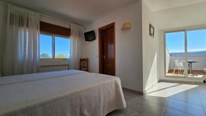 sypialnia z łóżkiem i dużym oknem w obiekcie Hotel La Costera w mieście A Lanzada