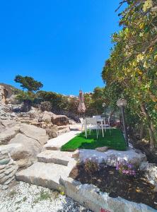 a patio with a table and an umbrella and some rocks at Villa Nereide - Baia Santa Reparata in Santa Reparata