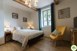 una camera da letto con un letto, una sedia e una finestra di Maison d'hôtes "La Clef des Champs" Piscine Ortance a Sajas