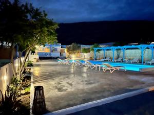 a group of chairs and a swimming pool at night at Family Villages Santorini in Vlychada Beach