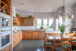 una cocina con armarios de madera y una mesa con sillas. en Casa entre Santander y Cabárceno con piscina, en Revilla de Camargo