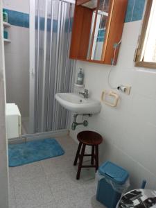 a bathroom with a sink and a stool at Casa vacanza Ligustro appartamento il gabbiano in SantʼAntìoco