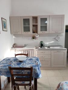 a kitchen with a table with chairs and a sink at Casa vacanza Ligustro appartamento il gabbiano in SantʼAntìoco