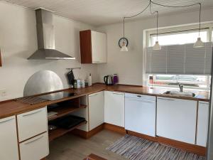 cocina con armarios blancos, fregadero y ventana en Nice and Cozy family house at Billund Center, en Billund
